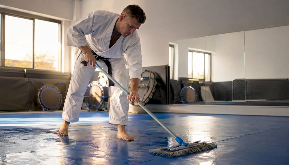 Ein Mann putzt die Matten im Dojo gründlich sauber.