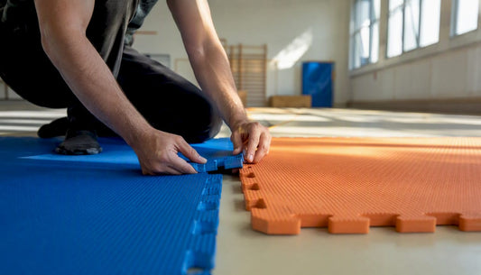 Nahaufnahme: Hände legen Sportmatten präzise aneinander.