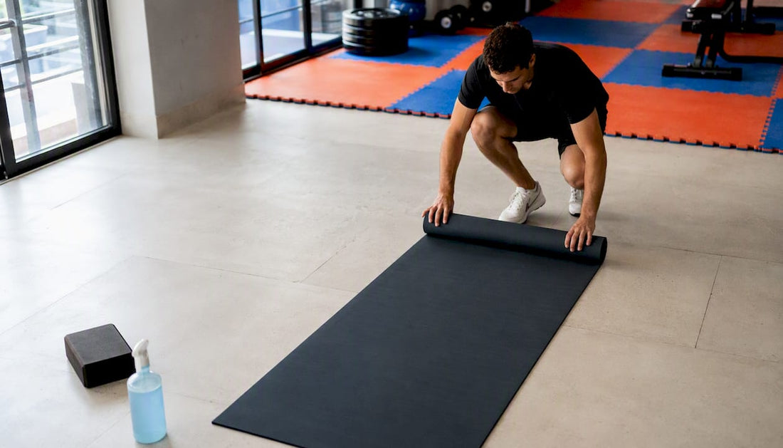 Im Fitnessstudio wird eine Turnmatte sorgfältig ausgerollt.