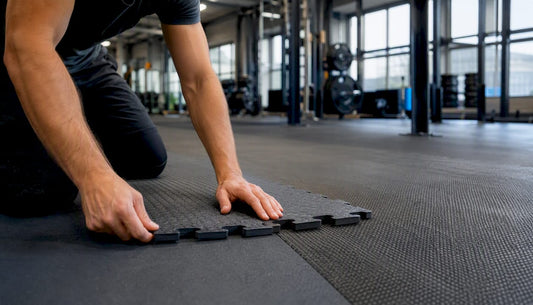 Hände setzen einzelne Fitnessmatten wie Puzzlestücke zusammen