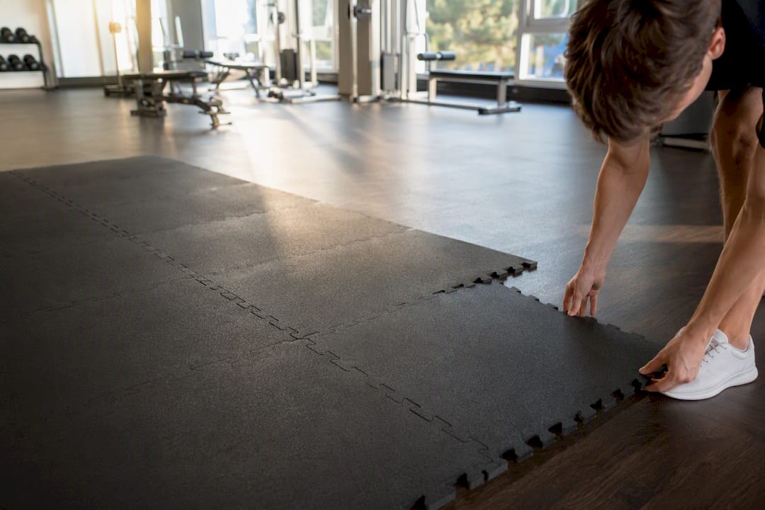 Mit geschickten Händen werden Fitnessmatten sorgfältig auf dem Boden des Studios ausgelegt.