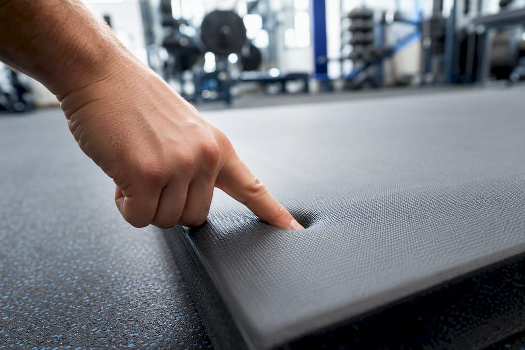 Hand drückt auf eine dichte Schaumstoff-Sportmatte, Nahaufnahme