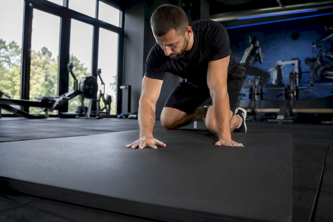 Hand, die auf eine strukturierte Fitnessmatte drückt